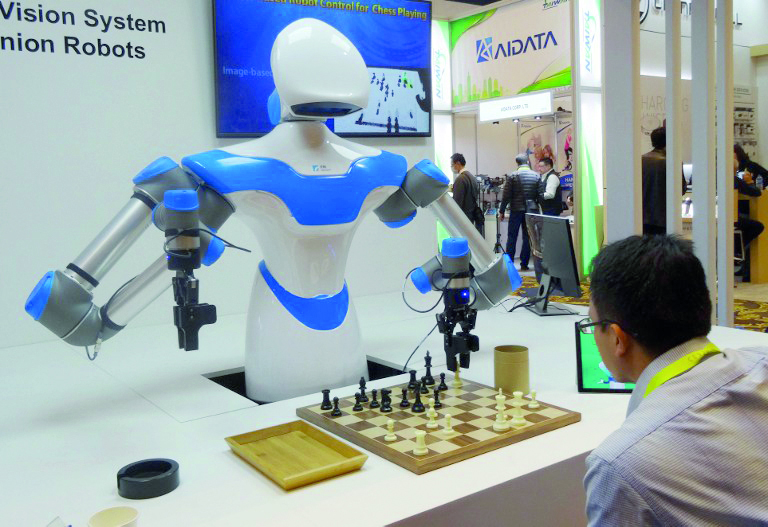 A robot developed by Taiwan engineers moves chess pieces on a board against an opponent, ,at the 2017 Consumer Electronic Show (CES) in Las Vegas, Nevada on January 8, 2017.    The robot developed by Taiwan's Industrial Technology Research Institute, which spent the week playing games against opponents at the Consumer Electronics Show, was displaying what developers call an "intelligent vision system" which can see its environment and act with greater precision than its peers. / AFP PHOTO / Rob Lever
